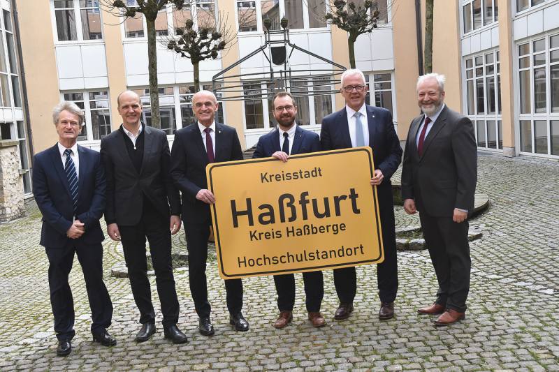 Landrat Wilhelm Schneider überreicht zusammen mit dem Präsidenten der THWS und dem Leiter des Technologietransferzentrums ein Ortsschild an den Bürgermeister der Stadt Haßfurt